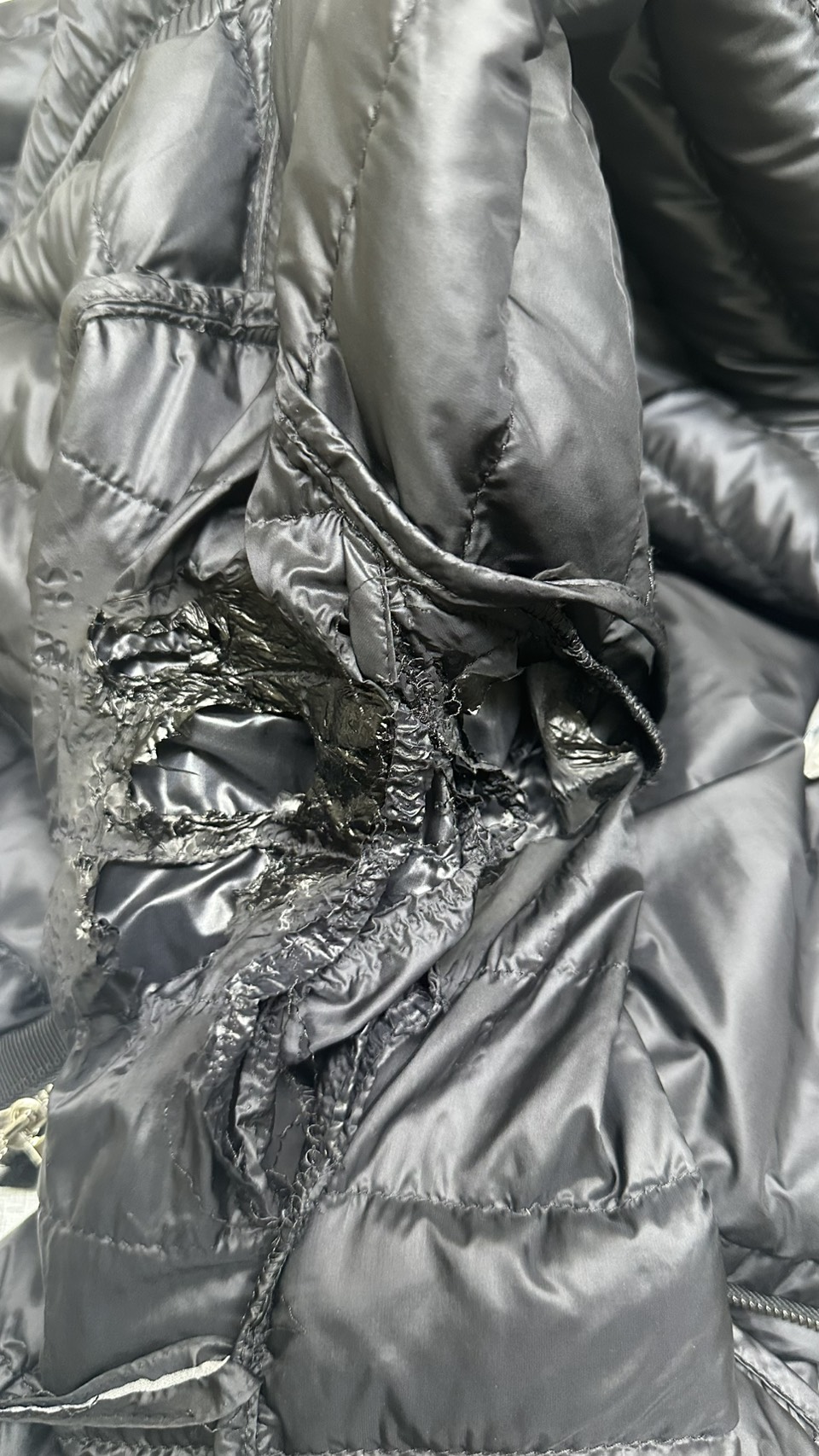 A melted hole in the shoulder of a black down jacket